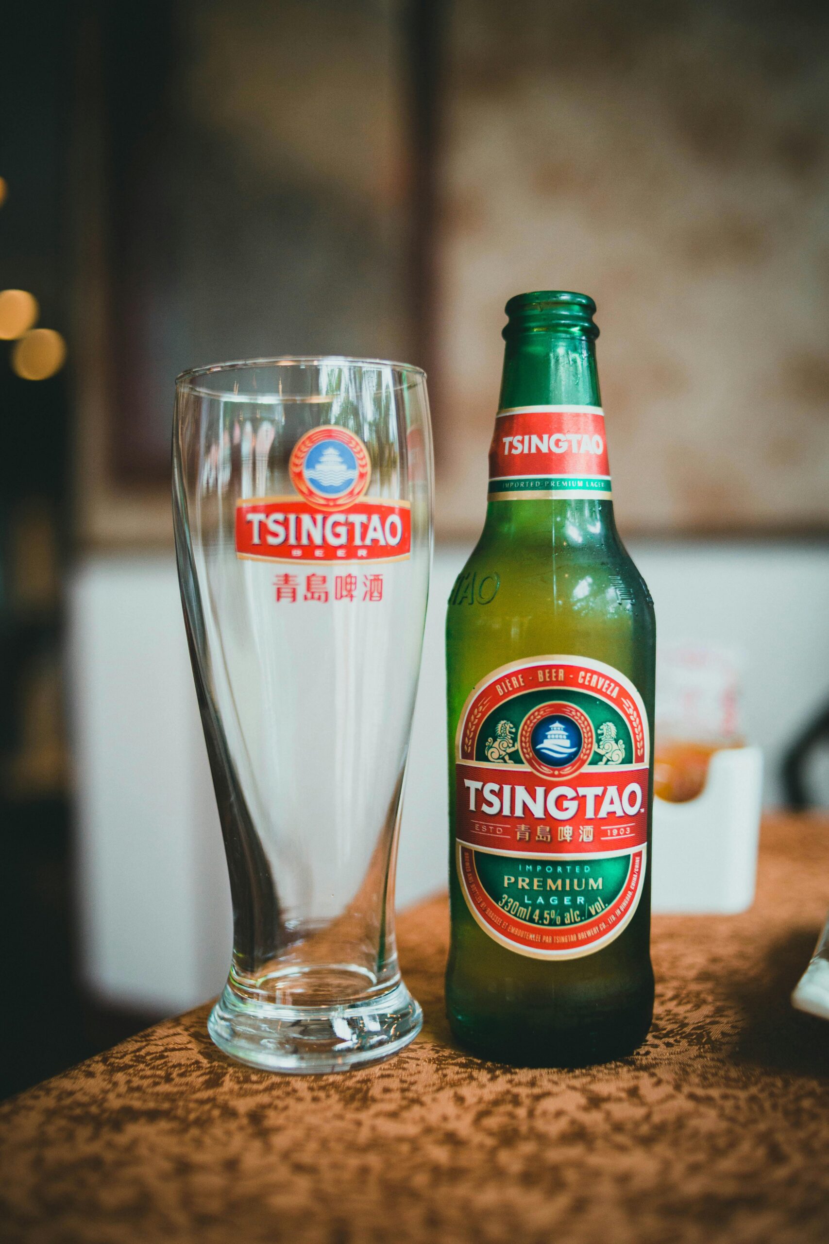 service-1 Close-up of Tsingtao beer bottle with glass in a pub setting.